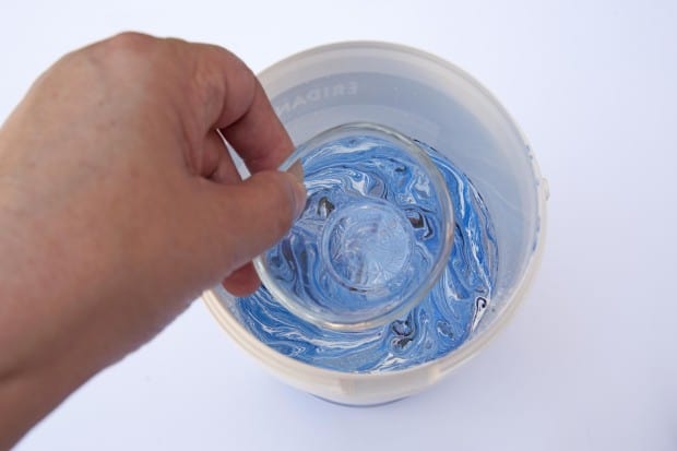 Sumergiendo la pieza de cristal en el bote con las pinturas de uñas mezcladas